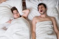 Young couple is lying in bed. Man is snoring and woman is covering her ears. Royalty Free Stock Photo