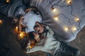 Young couple is lying on floor, smiling and hugging on background of glowing lightbulbs. Royalty Free Stock Photo