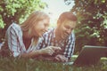 Young couple lying on the grass. Happy couple using laptop. Royalty Free Stock Photo