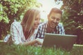 Young couple lying on the grass. Happy couple using laptop. Royalty Free Stock Photo