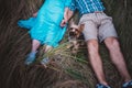 Young couple lying on the grass holding hands and small dog between them Royalty Free Stock Photo