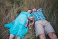 Young couple lying on the grass holding hands and small dog between them Royalty Free Stock Photo