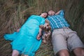 Young couple lying on the grass holding hands and small dog between them Royalty Free Stock Photo