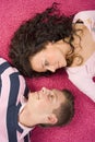 Young couple lying on the pink carpet