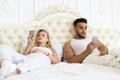 Young Couple Lying Separate In Bed, Serious Upset Hispanic Man And Woman Using Cell Smart Phone Royalty Free Stock Photo