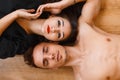 Young couple lying on the wooden floor and looking up. top view Royalty Free Stock Photo