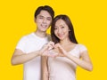 Young couple make heart figure with hands.Isolated on yellow background