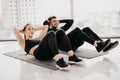 Young couple make sits up at gym. Attractive woman and handsome muscular man are training in light modern gym. Abs exercises Royalty Free Stock Photo