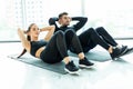 Young couple make sits up at gym. Attractive woman and handsome muscular man are training in light modern gym. Abs exercises Royalty Free Stock Photo