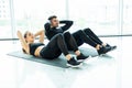 Young couple make sits up at gym. Attractive woman and handsome muscular man are training in light modern gym. Abs exercises Royalty Free Stock Photo