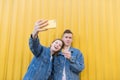 Young couple makes selfie on a background of yellow wall