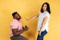 Young couple man making a proposal to his girlfriend, woman refusing, showing stop palm gesture.