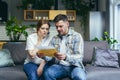 Young couple man and pregnant woman at home sitting on sofa, frustrated and sad, got a bad letter Royalty Free Stock Photo