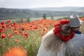 A young couple of man and woman in bright clothes are sitting with their backs to the audience in an embrace on a flowering poppy Royalty Free Stock Photo