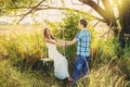 Young couple man and woman girlfriend and boyfriend wife and husband holding hands in park on tree swing in sunset. Beautiful Royalty Free Stock Photo