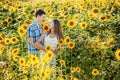 Young couple man and woman girlfriend and boyfriend wife and husband standing in sunflowers field looking at each other. Love,