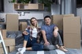 Young couple man and woman hugging together happy looking at camera, sitting on the floor of a new apartment, happy multiracial Royalty Free Stock Photo