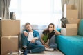 Young couple man and woman looking tired sitting on the floor during moving to new appartment unpacking boxes, , moving process Royalty Free Stock Photo