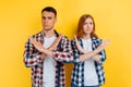 Young couple, man and woman, showing stop and forbid gesture, on yellow background