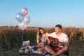 A young couple man and woman are sitting on plaid, summer in a wheat field. Relaxing on nature of playing the guitar Royalty Free Stock Photo