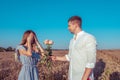 Young couple man woman, summer wheat field, happy smiling gives gift, bouquet of roses, surprise offer. Concept love Royalty Free Stock Photo