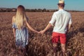 A young couple man woman, summer in wheat field, hold hands, walk and rest. Concept of love, date, emotion, tenderness Royalty Free Stock Photo