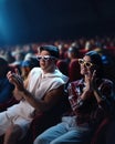 Young couple, man and woman wearing 3D glasses, sitting in cinema and watching movie, premier. Applauding and smiling Royalty Free Stock Photo