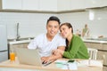 Young couple managing finances, reviewing their bank accounts using laptop computer and calculator at modern kitchen Royalty Free Stock Photo