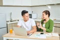 Young couple managing finances, reviewing their bank accounts using laptop computer and calculator at modern kitchen Royalty Free Stock Photo