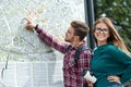 Young couple with a map in the city. Happy tourists sightseeing city with map Royalty Free Stock Photo