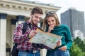 Young couple with a map in the city. Happy tourists sightseeing city with map Royalty Free Stock Photo