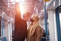 Young couple in medical masks holding handrails in subway car. Coronavirus pandemic.