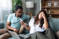 Young couple man and woman, roommates sitting at home on sofa having issue with financial debt, overspending and earnings, cant