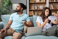 Young couple man and woman, roommates sitting at home on sofa having issue with financial debt, overspending and earnings, cant