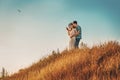 Young couple man and woman girlfriend and boyfriend wife and husband standing on hill looking at bird in sky. Love, romance,
