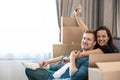 Young couple man and woman looking excited having break on the sofa during moving to new appartment unpacking boxes, , moving