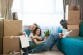 Young couple man and woman looking satisfied sitting on the floor hugging during moving to new apartment unpacking boxes, , moving Royalty Free Stock Photo