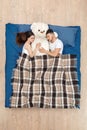 Bedtime. Young couple sleeping on bed top view under blanket hugging teddy peaceful Royalty Free Stock Photo