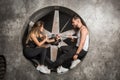 A young couple a man and a woman with a playful mood, fashionable and sporty look sit near an industrial fan in the factory with a Royalty Free Stock Photo