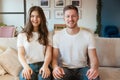 Young couple man and woman sitting on the sofa looking happy, grimacing mood