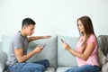 Young couple with mobile phones sitting on sofa at home Royalty Free Stock Photo