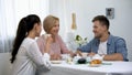 Young couple and mother-in-law drinking tea, sincerely laughing, time together