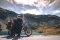 Young couple of motorcycle travelers in the autumn mountains of Romania. Moto tourism and moto travellers lifestyle while
