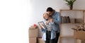 young couple move at new home standing take out unpack belongings from carton boxes holds frame looks at photo share