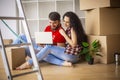 Young couple moving in new home.Sitting and relaxing after unpacking.Looking something on laptop. Young couple Royalty Free Stock Photo