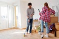 Young couple moving in new home. Unpacking box containers and cleaning.