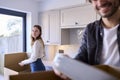 Young Couple Moving Into New Home Unpacking Boxes In Kitchen Together Royalty Free Stock Photo