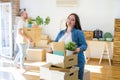 Young couple moving to new apartment, beautiful woman moving cardboard boxes and smiling happy