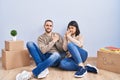 Young couple moving to a new home holding symbolic gun with hand gesture, playing killing shooting weapons, angry face