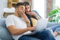 Young couple moving to a new home relaxing sitting on the sofa using computer laptop, smiling happy for moving to new apartment Royalty Free Stock Photo